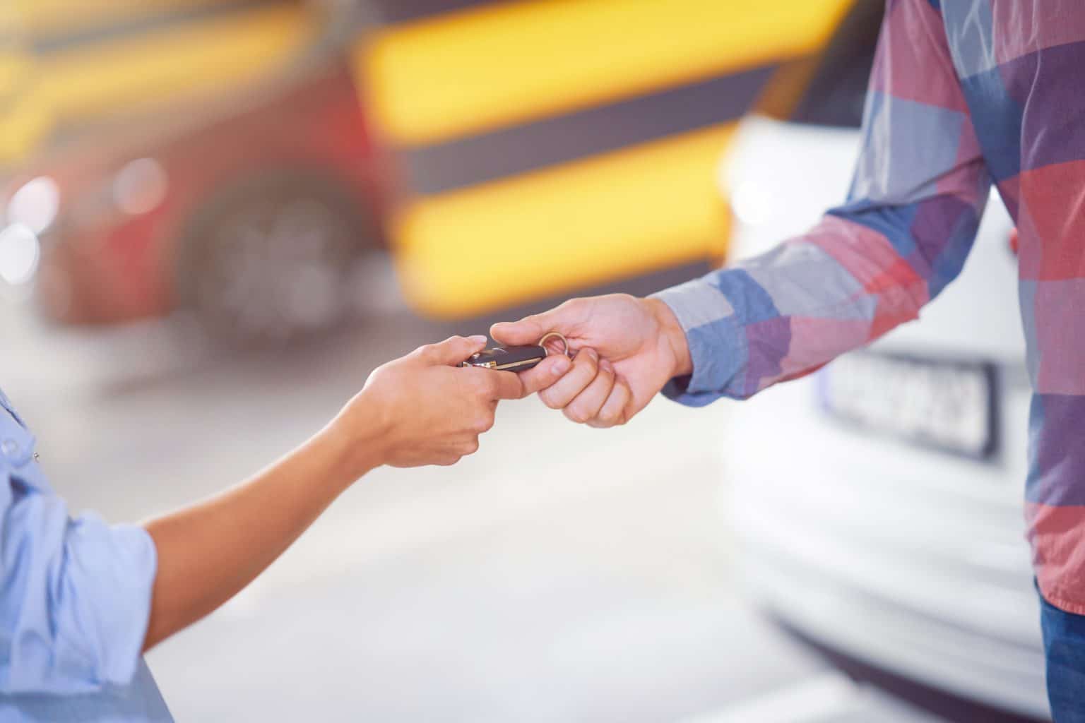 Midsection of car dealer giving keys to a customer