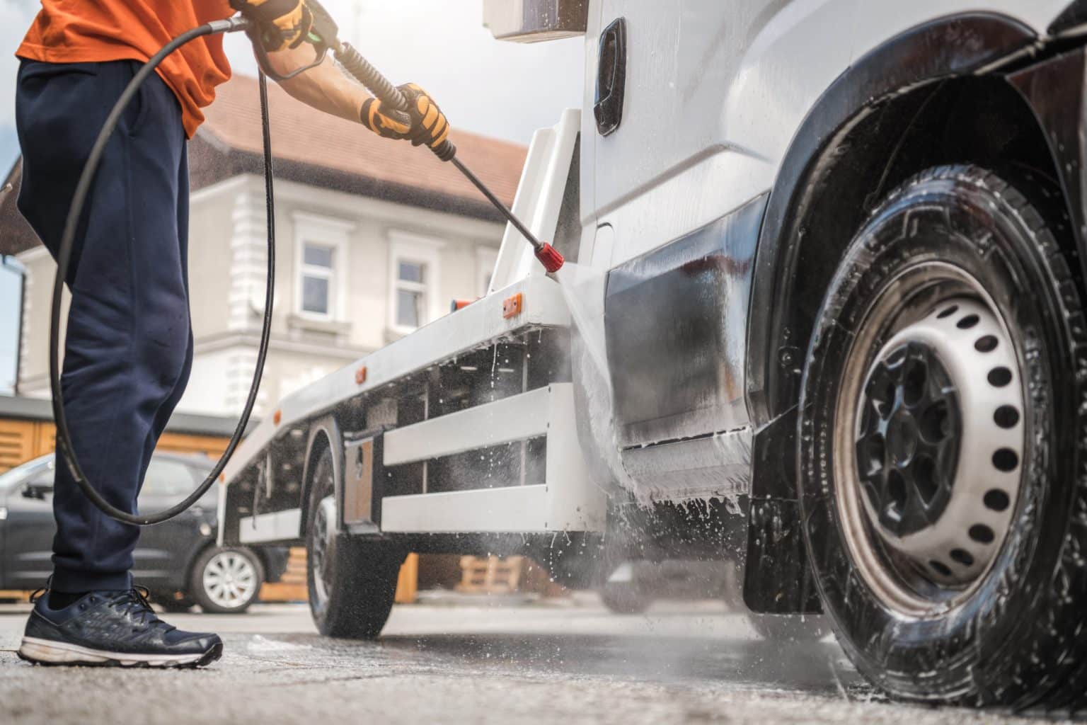 Caucasian Worker in His 40s Power Washing His Commercial Vehicle Towing Truck Inside Manual Car Wash.
